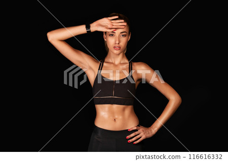 Sporty Lady Wiping Sweat From Forehead After Intensive Workout Training Over Black Background. Studio Shot Sporty Lady Wiping Sweat From Forehead After Intensive Workout Training Over Black Background. Studio Shot 116616332