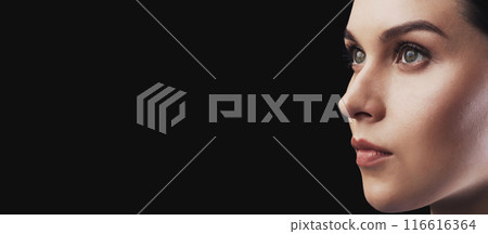 A close-up shot of a womans profile against a dark background. She is looking off to the side with a serious expression. 116616364