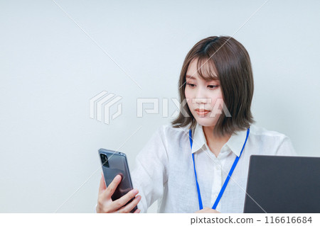 檢查她的智慧型手機的年輕辦公室女士 116616684