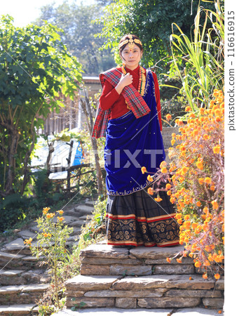 a villager girl dressing in Gurung traditional dressing walk down the staircase and look at camera  116616915