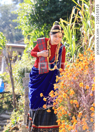 a villager girl dressing in Gurung traditional dressing walk down the staircase and look at camera  116616916