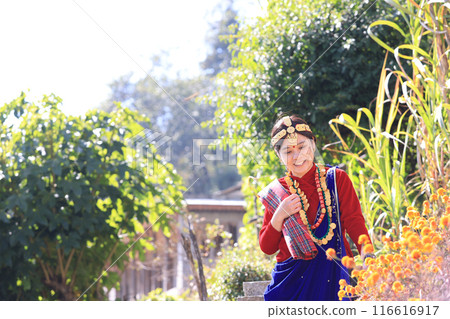 a villager girl dressing in Gurung traditional dressing walk down the staircase and look at camera  116616917
