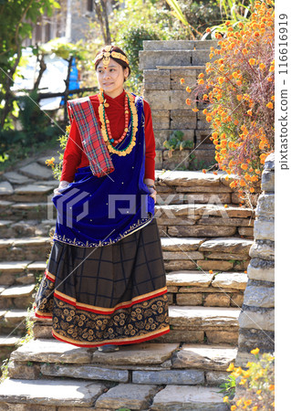 a villager girl dressing in Gurung traditional dressing walk down the staircase and look at camera  116616919
