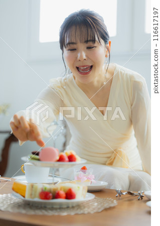 A woman eating sweets at a cafe 116617197