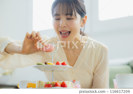 A woman eating sweets at a cafe 116617209