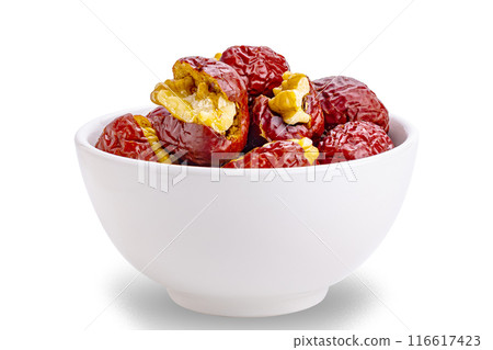 Side view of crunchy walnut stuffed red chinese jujube in white ceramic bowl. 116617423