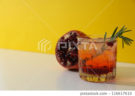 Red cocktail with fresh pomegranate on a yellow background Red cocktail with fresh pomegranate on a yellow background 116617610