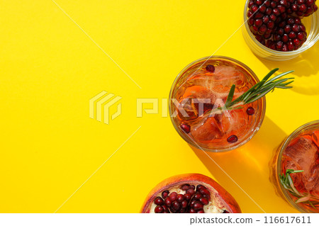 Red cocktail with fresh pomegranate on a yellow background Red cocktail with fresh pomegranate on a yellow background 116617611