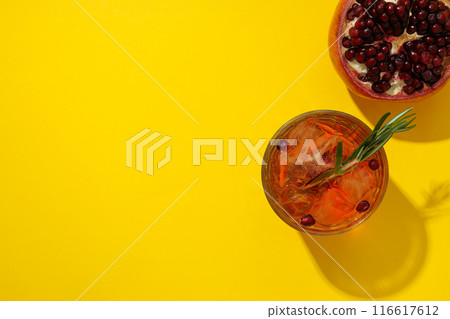 Red cocktail with fresh pomegranate on a yellow background Red cocktail with fresh pomegranate on a yellow background 116617612