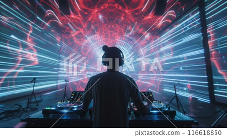 A DJ stands behind a mixing board with headphones on, mixing music in front of a projection of colorful lights. A DJ stands behind a mixing board with headphones on, mixing music in front of a projection of colorful lights. 116618850
