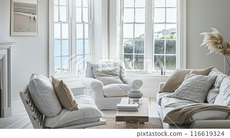 Interior of a living room with white walls, sofa and cushions. Sitting room in coastal cottage with sea view. Luxury lounge room 116619324