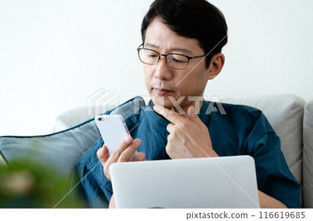 man using computer on sofa 116619685