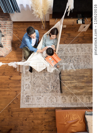 A family enjoying a relaxing time in a living room with a hammock A family enjoying a relaxing time in a living room with a hammock 116620016