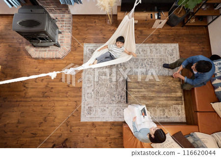 A family enjoying a relaxing time in a living room with a hammock A family enjoying a relaxing time in a living room with a hammock 116620044