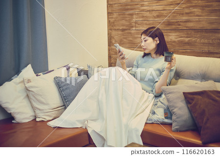 A woman using a smartphone on a sofa A woman using a smartphone on a sofa 116620163