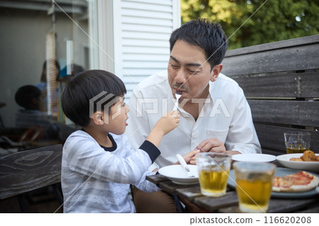 Father and son having a fun meal on the balcony Father and son having a fun meal on the balcony 116620208