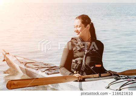 Woman sea kayak. Happy smiling woman in kayak on ocean, paddling with wooden oar. Calm sea water and horizon in background. Active lifestyle at sea. Summer vacation. 116621610