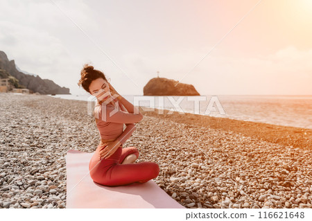 Middle aged well looking woman with black hair, fitness instructor in leggings and tops doing stretching and pilates on yoga mat near the sea. Female fitness yoga routine concept. Healthy lifestyle 116621648