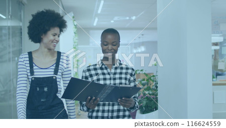 Diverse colleagues and African American intern discuss papers while walking Diverse colleagues and African American intern discuss papers while walking 116624559