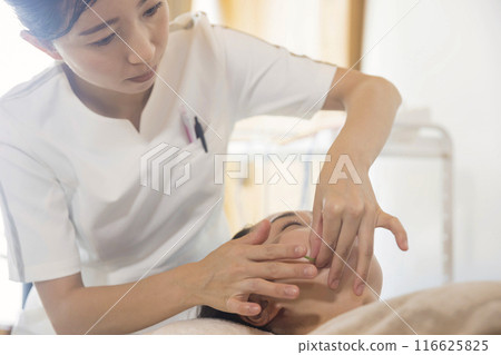 Acupuncturist performing cosmetic acupuncture Acupuncturist performing cosmetic acupuncture 116625825