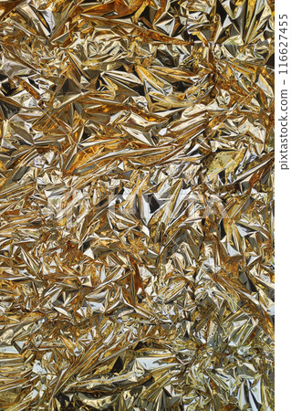 Crumpled golden foil shining texture background 116627455