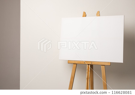 A blank canvas rests on a wooden easel against a neutral background, with copy space A blank canvas rests on a wooden easel against a neutral background, with copy space 116628081
