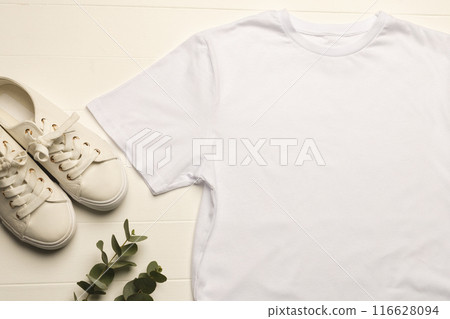 White t-shirt and sneakers on wood with plant for minimalist fashion promo. 116628094