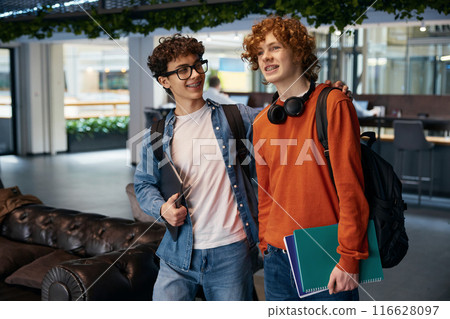 Two positive boys walking in coworking office together 116628097