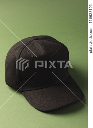 A black baseball cap is positioned against a green background, with copy space A black baseball cap is positioned against a green background, with copy space 116628103