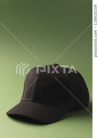 A plain black baseball cap is positioned against a green background, with copy space A plain black baseball cap is positioned against a green background, with copy space 116628104