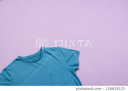 A blue t-shirt is laid out on a purple background, with copy space A blue t-shirt is laid out on a purple background, with copy space 116628125