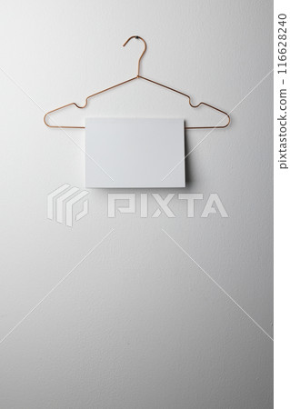 A blank white sheet hangs on a hanger against a wall with copy space A blank white sheet hangs on a hanger against a wall with copy space 116628240