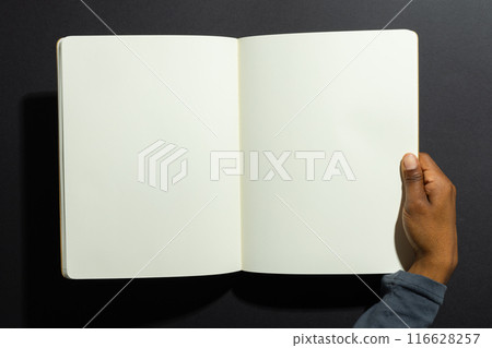 African American hand holding an open blank notebook, with copy space African American hand holding an open blank notebook, with copy space 116628257