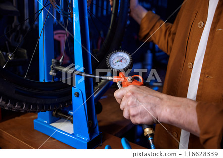 Closeup bike mechanic checking tire pressure or pumping bicycle wheel Closeup bike mechanic checking tire pressure or pumping bicycle wheel 116628339
