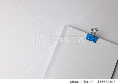A blue paper clip on white sheets, with copy space 116628407