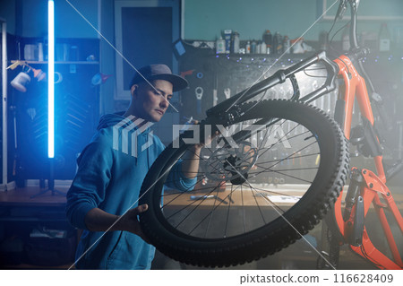 Professional bicycle mechanic installing front wheel at workshop Professional bicycle mechanic installing front wheel at workshop 116628409