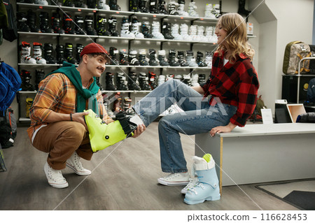 Happy man and woman couple choosing ski boots at sportive shop 116628453