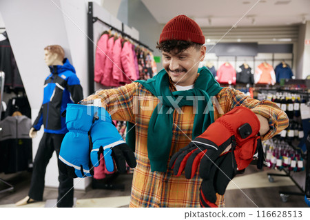 Smiling positive hipster man bicyclist choosing sportive protective gloves 116628513