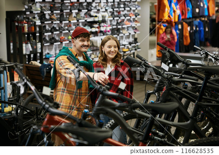 Happy couple choosing bicycle at sports shop Happy couple choosing bicycle at sports shop 116628535