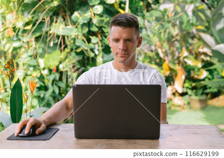 Focused man using laptop, successful freelancer working online on computer sitting in modern kitchen 116629199