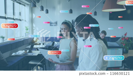 Image of social media icons over diverse man and woman discussing over a laptop at office 116630121