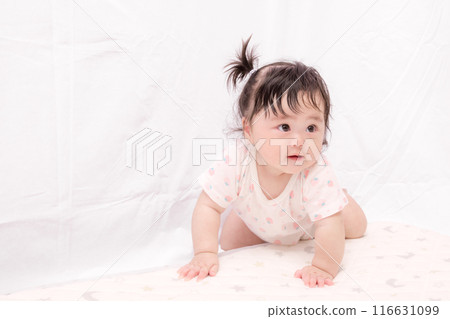 [A baby with tied hair starting to crawl] 116631099