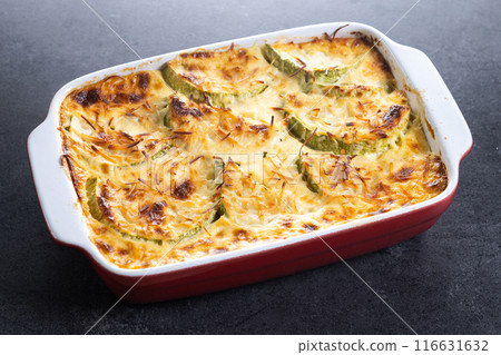 Casserole with cheese and gratin zucchini on black stone background 116631632