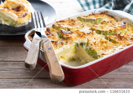 Casserole with cheese and gratin zucchini on wooden table 116631633