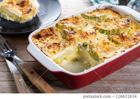 Casserole with cheese and gratin zucchini on wooden table 116631634