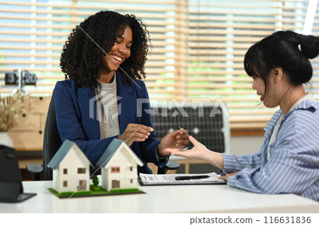 Smiling African American giving house keys to to new owner. Property purchase concept Smiling African American giving house keys to to new owner. Property purchase concept 116631836