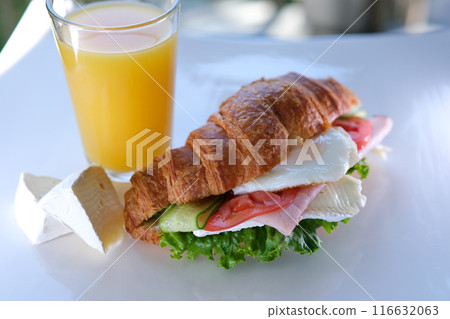 Zoom-in close up view of breakfast meal: croissant sandwich with bacon and scrambled eggs. Original tasty meal with meat served at Bali cafeteria in morning time 116632063