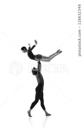 Elevated elegance. Young ballet dancer lifting ballerina harmonizing their moves against white studio background. Monochrome filter. Elevated elegance. Young ballet dancer lifting ballerina harmonizing their moves against white studio background. Monochrome filter. 116632349
