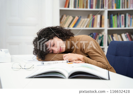 Exhausted woman architect working with blueprints in library and falling asleep Exhausted woman architect working with blueprints in library and falling asleep 116632428