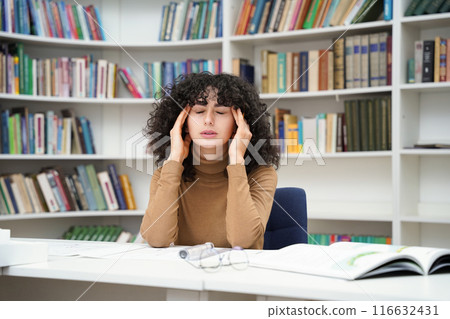 Woman interior design student working on blueprint of new project with terrible headache in library 116632431